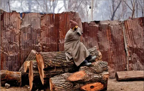  ??  ?? A man sits on a log on a cold winter morning in Srinagar on Thursday. REUTERS