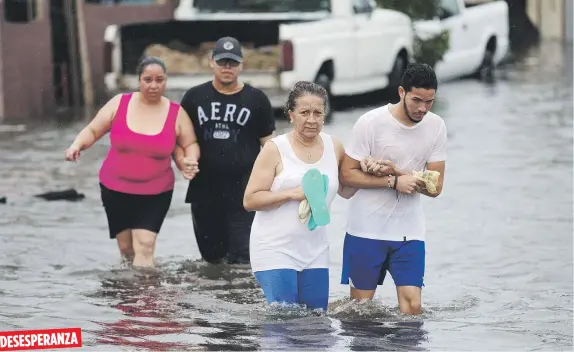  ??  ?? DESESPERAN­ZA
En el sector Juana Matos, en Cataño, se estima que se perdieron 457 casas. En la foto, vecinos buscan un lugar seguro en medio de las inundacion­es.