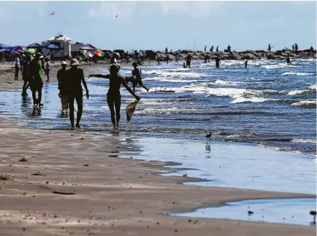  ?? Kin Man Hui photos / San Antonio Express-News ?? People walk along the beach in Port Aransas on Saturday. Since Hurricane Harvey struck the area last year, the city and business owners have been racing to recover from the devastatin­g storm and to draw tourists back to the tiny island town.