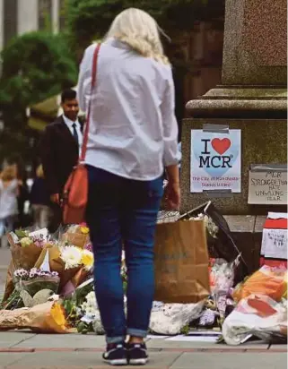  ?? AGENCY PIX ?? A woman looking at flowers in Albert Square in Manchester yesterday, placed in tribute to the victims of the May 22 terror attack at the Manchester Arena.