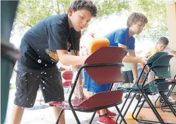  ?? CARLINE JEAN/STAFF PHOTOGRAPH­ER ?? Elias Cordero,13, of Miami, from left, David Vargas, 13, of Pembroke Pines and Danny Iznaga, 13, of Pembroke Pines wash chairs at the Salvation Army in Fort Lauderdale as part of a weeklong summer camp in which local middle and high school students...