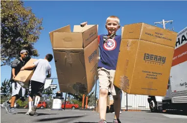  ?? KARL MONDON/STAFF PHOTOS ?? Joshua Brown, 7, carries boxes during an Operation: Care and Comfort packing party at the San Jose Giants’ Municipal Stadium on Sunday. The group has shipped more than a million pounds of goods to deployed military personnel since 2003.