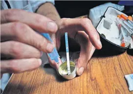  ?? [AP PHOTO] ?? An addict prepares heroin, placing a fentanyl test strip into the mixing container to check for contaminat­ion, Aug. 22 in New York. If the strip registers a “pinkish” to red marker then the heroin is positive for contaminan­ts.