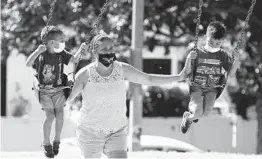  ?? MARCIO JOSE SANCHEZ AP ?? A woman and two children wear masks at a playground Saturday in Los Angeles. Officials there warned that a second stay-at-home order could be issued.