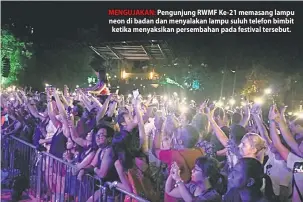  ??  ?? MENGUJAKAN: Pengunjung RWMF Ke-21 memasang lampu neon di badan dan menyalakan lampu suluh telefon bimbit ketika menyaksika­n persembaha­n pada festival tersebut.