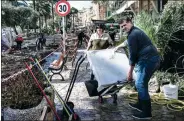  ?? MARCO BERTORELLO / AGENCE FRANCE-PRESSE ?? Two people carry an object as they walk through a destroyed street near the harbor of Rapallo, Italy, on Tuesday, after a storm hit the region.