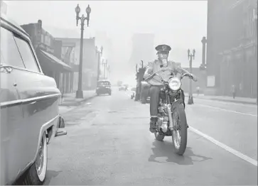  ?? Los Angeles Times Archive/UCLA ?? THE WAY IT WAS: In 1955, a motorcycli­st uses a gas mask as he rides through the smog in downtown L.A.