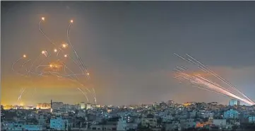  ?? AFP ?? Rockets (right) seen in the night sky, fired towards Israel from Beit Lahia in the northern Gaza Strip on Friday. Israel -- its missile defence system’s contrails on the left -- bombarded Gaza with artillery and airstrikes.
Story on page 11