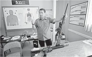  ??  ?? Alex Shkop, owner of Guns and Range Training Center, explains the difference between an AR-15 semi-automatic rifle and a bolt-action rifle during a demonstrat­ion at his business in West Palm Beach.