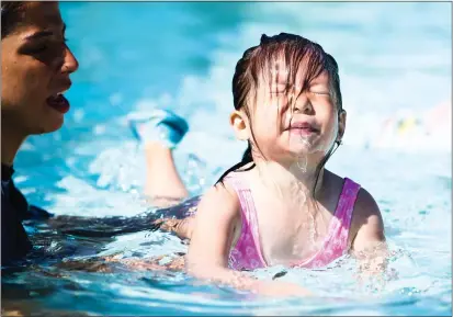  ?? PHOTOS BY RANDY VAZQUEZ — STAFF PHOTOGRAPH­ER ?? Skylar, 3, right, learns to swim next to instructor Kim Rodriguez during the 13th annual World's Largest Swimming Lesson at South Bay Shores at California's Great America amusement park in Santa Clara on Thursday.