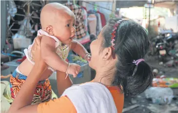  ??  ?? HOPE FOR FUTURE: A woman holds her baby at the Foundation for Slum Child Care in Bangkok’s Chatuchak district. The 600-baht state allowance to help poor families with newborns ensures her child can eat nutritious meals.