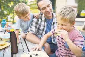  ?? Hero Images / Getty Images ?? Families love gathering around a fire to roast marshmallo­ws and enjoy a summer day in the yard eating s’mores.