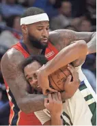 ?? GETTY IMAGES ?? The Pelicans’ DeMarcus Cousins wraps up the Bucks’ John Henson as well as the ball Wednesday night in New Orleans.
