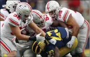  ?? PAUL SANCYA - STAFF, AP ?? FILE - Ohio State linebacker­s Tuf Borland (32), Davon Hamilton (53) and Malik Harrison (39) smother Michigan running back Hassan Haskins (25) in the second half of an NCAA college football game in Ann Arbor, Mich., in this Saturday, Nov. 30, 2019, file photo.