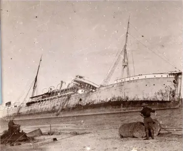  ?? (HMP) ?? ■ One of the German ships in Dar-es-Salaam harbour on 28 November 1914 was the 4,825ton mail steamship König – seen here beached after the Royal Navy attack. Her engine was disabled by a demolition charge during the raid. Inset: A cigarette card depicting Commander Henry Peel Ritchie’s VC action.