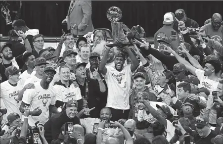  ?? AP ?? The Milwaukee Bucks celebrate with the championsh­ip trophy after defeating the Phoenix Suns in last season’s NBA Finals on July 20. The Bucks tip off their title defense against the Brooklyn Nets, who will be without the unvaccinat­ed Kyrie Irving.