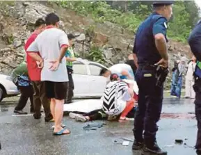  ?? [ FOTO ERIKA GEORGE/BH ] ?? Orang ramai menutup mayat mangsa yang maut dalam kemalangan di Jalan Kemunting, Bintulu, semalam.