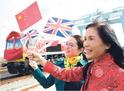  ?? Picture: AFP ?? TRAIN SPOTTING. People wave a Chinese flag and a Union Jack as they pose for photograph­s to witness the departure of a freight train transporti­ng containers laden with goods from the UK to Yiwu in the eastern Chinese province of Zhejiang.