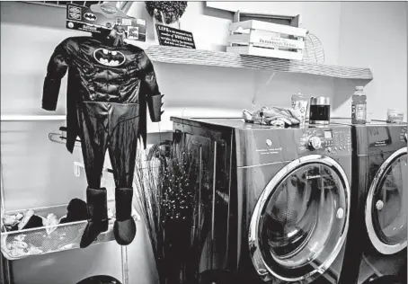  ?? ZBIGNIEW BZDAK/CHICAGO TRIBUNE PHOTOS ?? Colton Miller’s Batman costume hangs in the laundry room of his mother’s house in Joliet. He was shot to death before he had a chance to wear it.