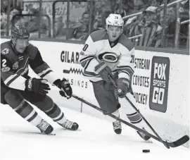  ?? RALPH FRESO/AP ?? Carolina's Sebastian Aho (20) skates with the puck behind the net as the Coyotes' Luke Schenn defends during the first period of Sunday’s game at Gila River Arena in Glendale.