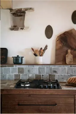  ??  ?? Kitchen Justine and Jean made the worktops themselves, using
black sandstone tiles from their workshop and aged sequoia Living room In this relaxed space sits an antique armchair inherited
from a family member and a vintage sofa, draped in linen and occupied by Nino the cat. On the homemade coffee table, a Moroccan teapot from La Maison Poétique is displayed alongside vases
(also seen below left) and cups by Epure ➤