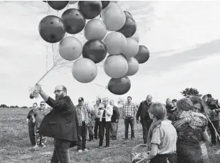  ??  ?? Kaleb Pomeroy carries balloons to be released at the grave of his sister, Annabelle, on Oct. 21, which would have been her 15th birthday. At right, their mother embraces Kaleb’s daughter.