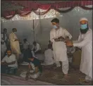  ??  ?? Kashmiri men carry rice plates before serving them to guests.