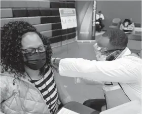  ??  ?? Valerie Penn-Bryant of Baltimore gets the COVID-19 vaccine Wednesday from pharmacy intern Henry Okoro at Baltimore City Community College.