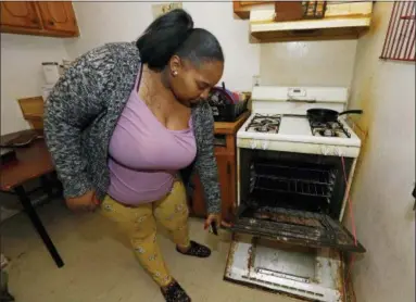  ?? AP PHOTO/ROGELIO V. SOLIS ?? In this Feb. 20 photo, Destiny Johnson shows the broken door to her oven that she uses string to hold together, in her apartment in Cedarhurst Homes, a federally subsidized, low-income apartment complex in Natchez, Miss. The complex failed a health and safety inspection in each of the past three years.