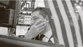  ?? Richard Drew / Associated Press ?? Specialist Ronnie Howard works at his post on the floor of the New York Stock Exchange Wednesday. A big gain from Apple helped drive the markets.