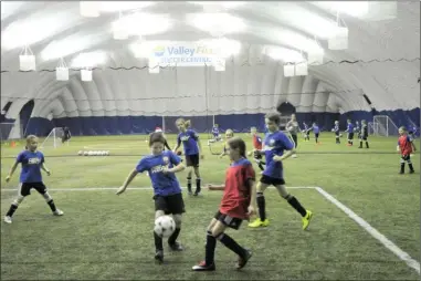  ?? GARY NYLANDER/The Daily Courier ?? Children practise their soccer skills Monday at Valley First Soccer Centre in Kelowna. Constructi­on of the indoor soccer dome was accomplish­ed in part through a major fundraisin­g drive. The cost for a similar facility in West Kelowna is much higher...