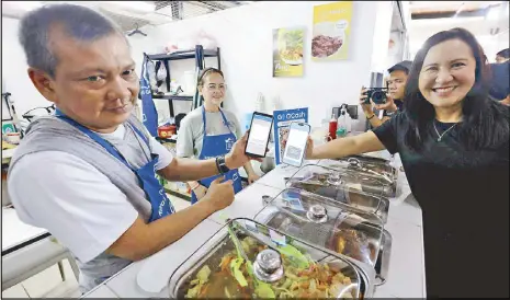  ?? MICHAEL VARCAS ?? Quezon City Mayor Joy Belmonte makes a purchase in a restaurant using a QR code during the launch of the Paleng-QR Ph at the Project 4 public market yesterday.