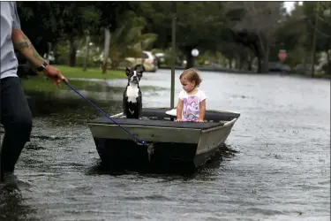  ?? CARLINE JEAN — SOUTH FLORIDA SUN-SENTINEL VIA AP ?? Lemay Acosta pulls his daughter Layla, 2, and dog Buster on a boat as they tour his flooded neighborho­od in Plantation, Fla., on Monday, Nov. 9, a day after Tropical Storm Eta made landfall in the Florida Keys and flooded parts of South Florida.