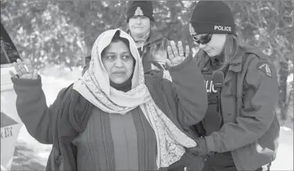  ?? The Canadian Press ?? An RCMP officer frisks as asylum claimant after she crossed the border into Canada from the United States with her two daughters, on March 17 near Hemmingfor­d, Que.