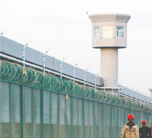  ?? THOMAS PETER / REUTERS FILES ?? Workers walk by the perimeter fence of what is officially known as a vocational skills education centre in Dabancheng in the Xinjiang Uyghur
Autonomous Region in China. Area residents told the BBC the facility is there to help people experienci­ng “problems with their thoughts.”