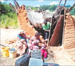  ??  ?? MR MUNYARADZI WARURE emerges from his cyclone hit kitchen while his wife Ms Tatenda Mutyada (middle) and a relative sit helplessly together with their children and belongings at Takawira Village in Mukanganwi Communal lands,Bikita