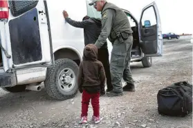  ?? John Moore / Getty Images ?? A child watches a Border Patrol agent search a fellow Central American immigrant after they crossed the border from Mexico into El Paso this month.