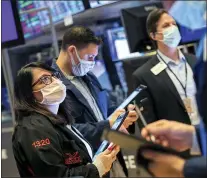  ?? COURTNEY CROW — NEW YORK STOCK EXCHANGE VIA AP ?? Phyllis Arena Woods, left, works with other traders Friday on the New York Stock Exchange floor. Stocks wobbled between small gains and losses on Wall Street Friday as rising technology stocks offset a slide in banks and energy companies.