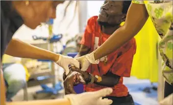  ?? Ramon Espinosa Associated Press ?? JEAN MARC Baptiste receives treatment for a bullet wound at a Doctors Without Borders emergency room in Port-au-Prince, Haiti. Doctors told him that he needed a plastic surgeon, which the hospital does not have.