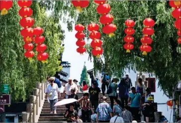  ?? JOHANNES EISELE/AFP ?? People walk over a bridge in a tourist area in the suburbs of Shanghai on May 22.