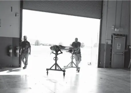  ?? [DOUG HOKE/ THE OKLAHOMAN] ?? Kratos employees move a target drone inside after testing its engine last year.