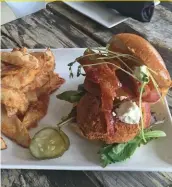  ??  ?? Bacon, lettuce, fried green tomato, goat cheese drizzled with roasted red pepper aioli with home fries. (Courtesy photo)