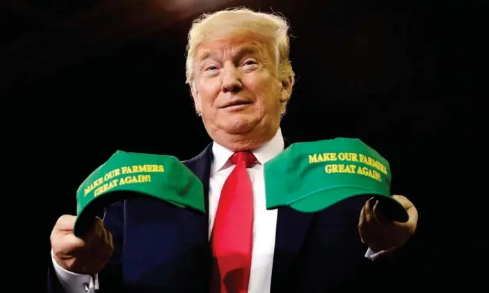  ?? Photograph: Kevin Lamarque/Reuters ?? Donald Trump with a pair of ‘Make America Great Again’ hats at a rally in Indiana in August last year. Trump tweeted: ‘The Farmers have been forgotten for many years. Their time is now!’