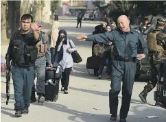  ?? WAKIL KOHSAR / AFP / GETTY IMAGES ?? Students from the American University of Afghanista­n, who were trapped inside the school during the attack, are escorted by police forces in Kabul, Thursday.