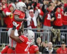  ?? JAY LAPRETE — THE ASSOCIATED PRESS ?? Ohio State receiver Johnnie Dixon, top, celebrates his touchdown against Michigan during the first half of an NCAA college football game Saturday in Columbus, Ohio.