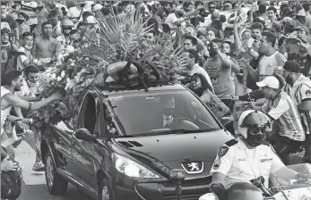  ?? RAUL FERRARI / TELAM VIA AFP ?? Fans crowd around the hearse carrying soccer legend Diego Maradona on its way from the Casa Rosada presidenti­al palace in Buenos Aires to the cemetery on Thursday.