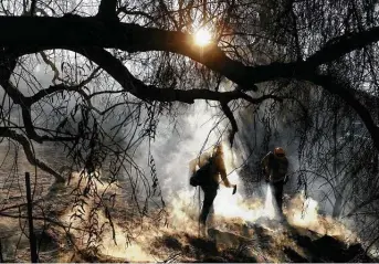  ?? Wally Skalij / TNS ?? Firefighte­rs extinguish hot spots from the Bond fire Friday in an unincorpor­ated area of Orange County.