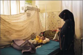  ?? ?? A woman changes the clothes of her baby Oct. 11 in the malnourish­ed ward of the Mohammed Khan Hospital in Sayedabad district, Wardak province.