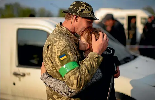  ?? AP ?? Hryhorii hugs his wife Oksana as they are reunited at a reception centre for displaced people in Zaporizhzh­ia on Monday. Thousands of Ukrainians continue to leave Russian occupied areas.