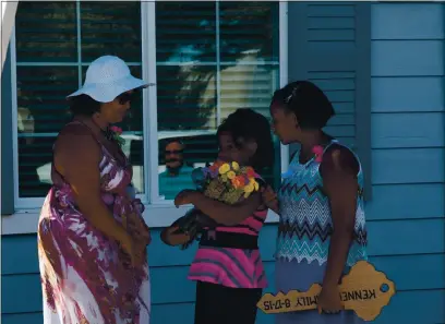  ?? CONTRIBUTE­D PHOTO — RICHARD SCHWAB ?? Left to right: Briana Kenner and her daughters, Shamia and Maishia, enjoy the flowers and the honorary key to their new home given to them by Habitat for Humanity at the dedication ceremony in 2015. Kenner and her family members put in over 500 hours of work and were helped by some 500-600 Habitat volunteers in building their new home.